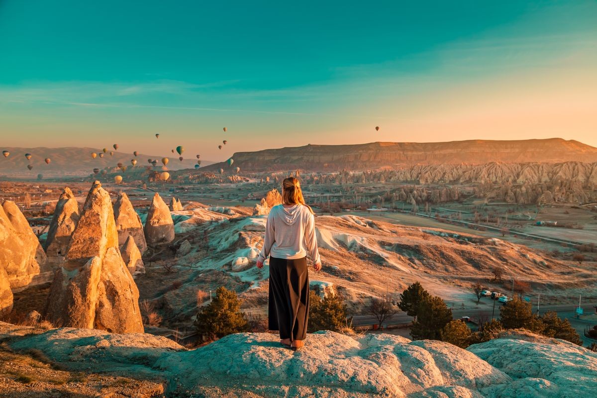 Girl watching the balloons and enjoying amazing view. Cappadocia, Goreme, Turkey.