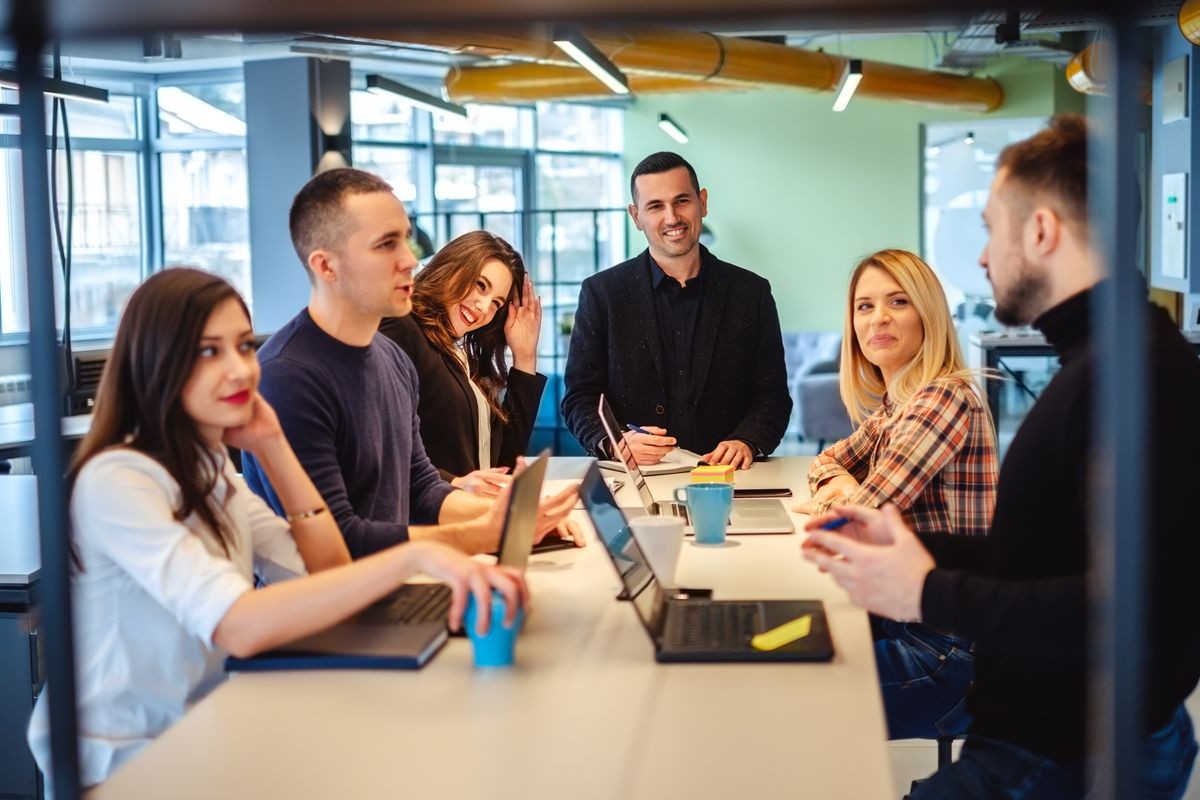 Colleagues looking at one man at the office meeting and smiling