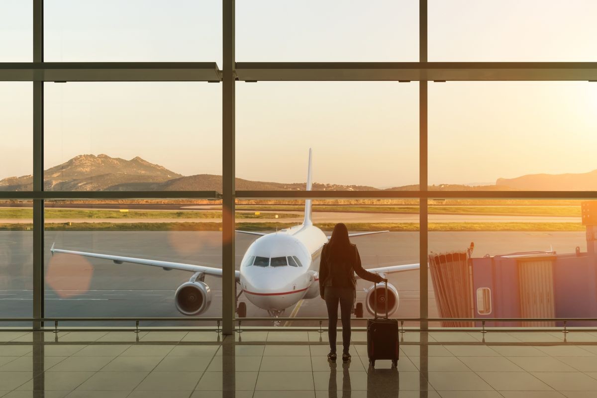 Young woman with suitcase in the departure hall at airport. Travel concept.